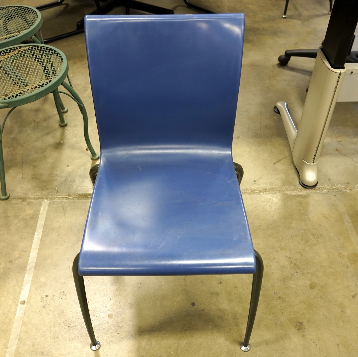 Blue institutional stacking chair featuring a molded plastic shell.