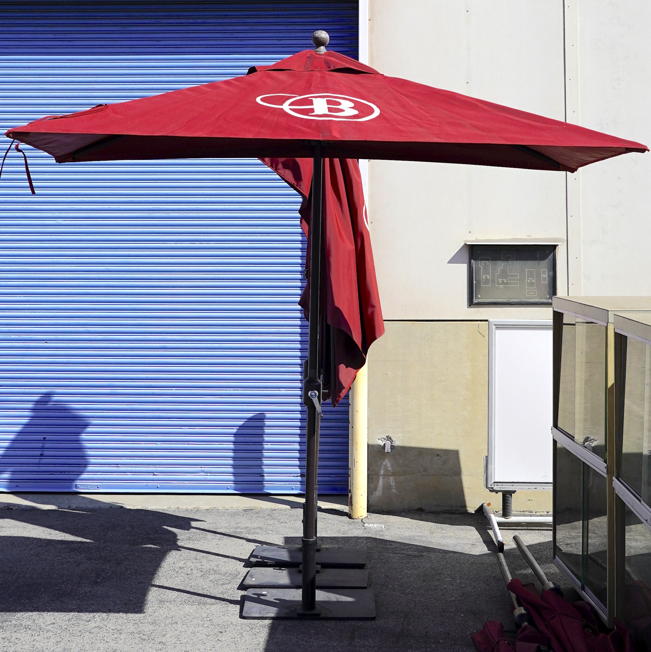 Outdoor red half umbrella with a dark brown metal base.