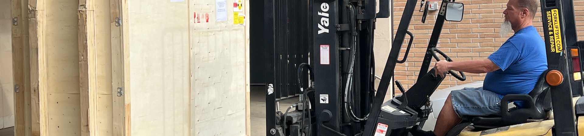A Receiving Services worker uses a forklift to load a crate onto a loading dock.